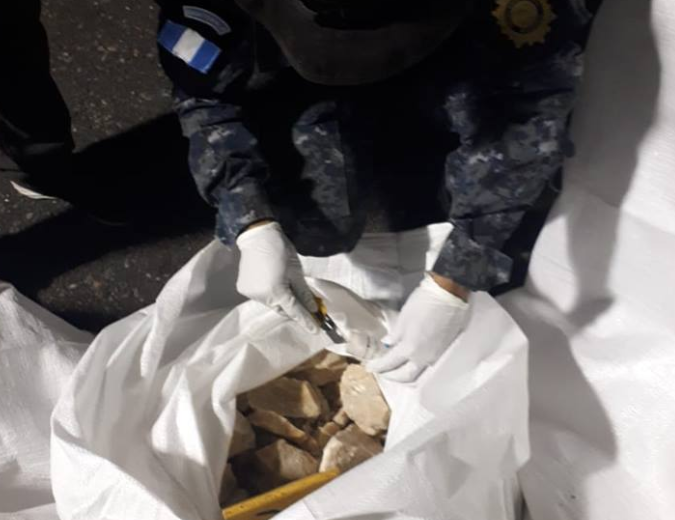 Agente observa parte de la droga decomisada en Escuintla. (Foto Prensa Libre: PNC).