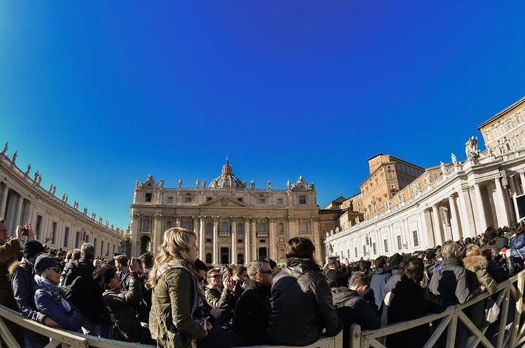 A crowd of faithful and tourists listen to Pope Francis (Top R) delivering his message from the window of the Apostolic palace overlooking St. Peter