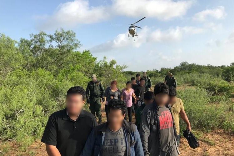 Migrantes aprehendidos en la frontera sur de EE. UU. son custodiados por guardias de la Patrulla Fronteriza. (Foto: CBP)