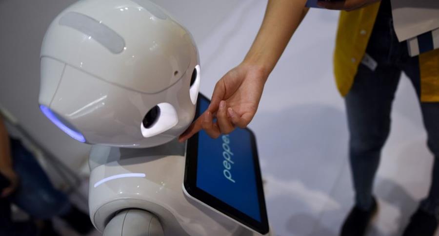   A robot that can be used in a shopping mall alternates with a woman at the World Robotics Congress in Beijing. (Photo Prensa Libre: AFP) 