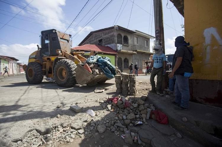 Grupo de simpatizantes del Gobierno de Ortega levantan adoquines de una barricada en Monimbo, Masaya. (EFE)